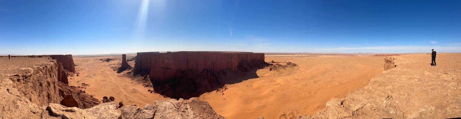 Hoggar Assekrem trek: cliff edge dropping to orange sand in the southern Algerian Sahara
