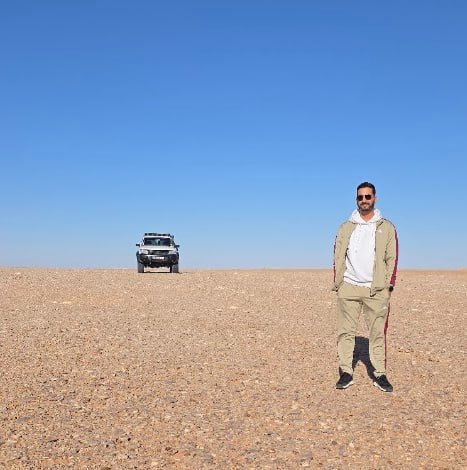 Timimoun tour: traveller and 4x4 on the open gravel plain of the Algerian Sahara